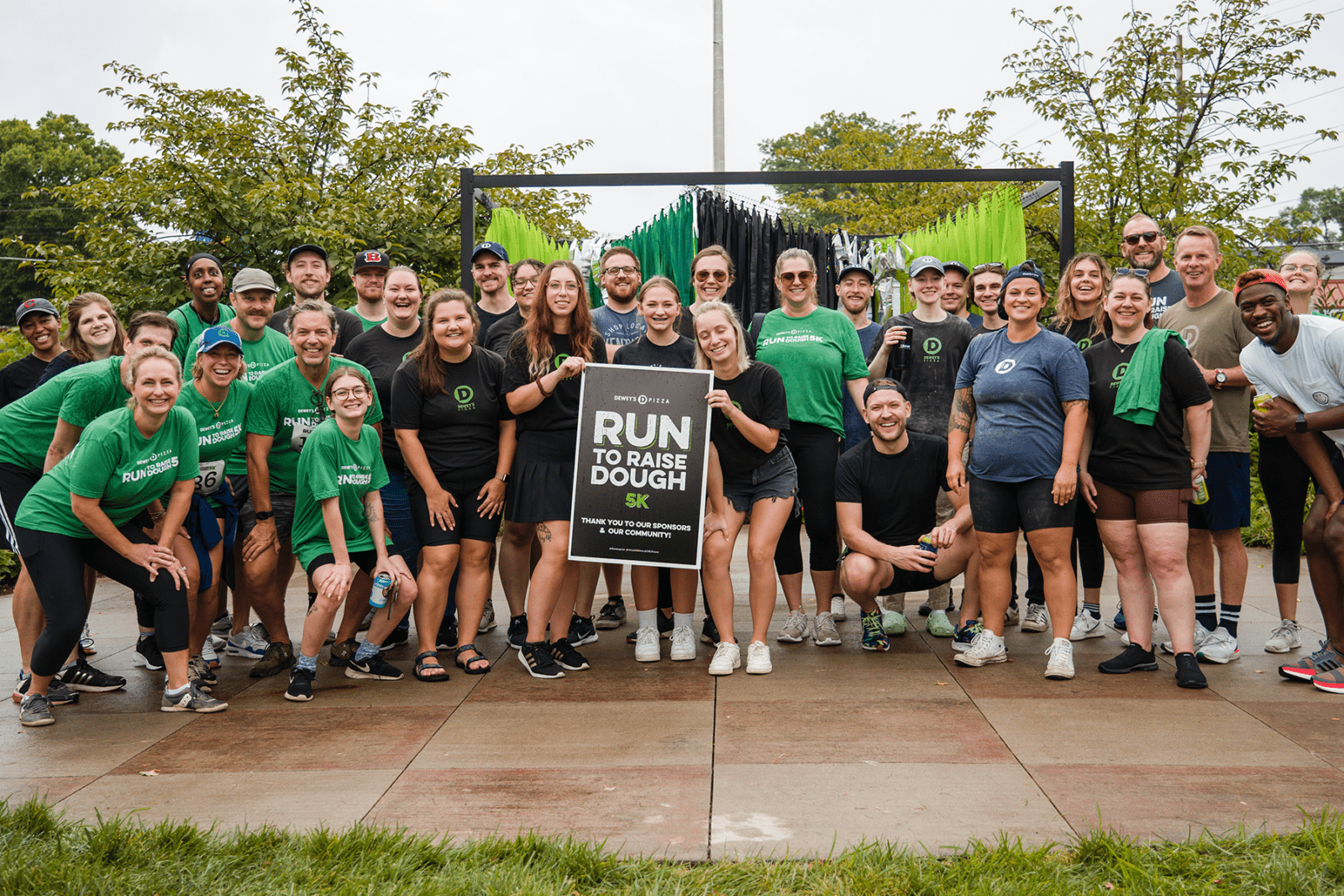 a group of runners hold up a run to raise dough 5k sign