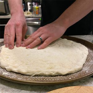 hands streach out a pizza dough