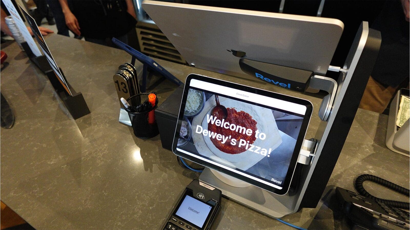 Close-up of a digital point-of-sale register on the counter at Dewey's Pizza, displaying a 